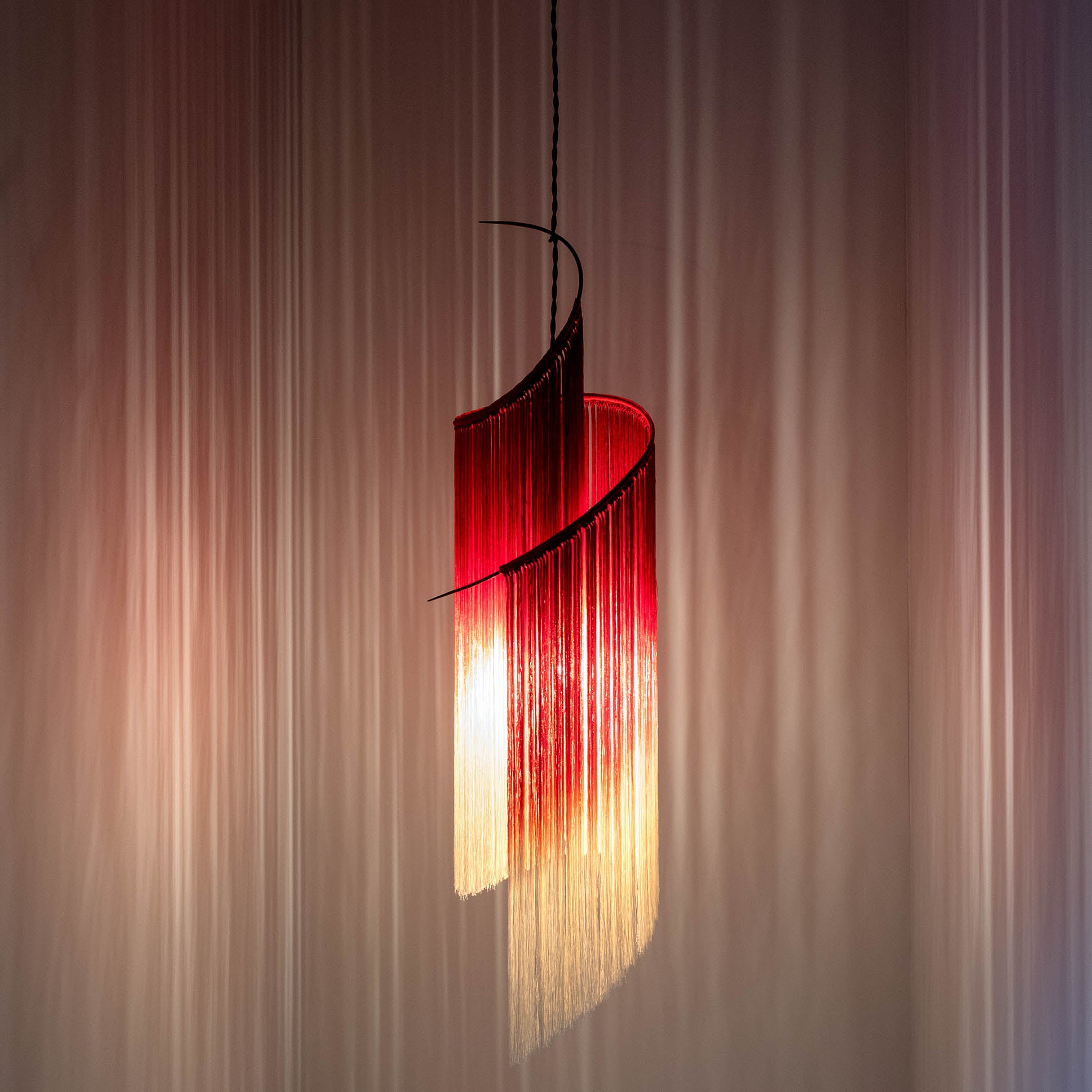 Serax Pendant Lamp Rey – rot-weiße Lampe als Spirale mit rot-weißem Farbverlauf in den Fäden in Bewegung, inszeniert im Lichtspiel